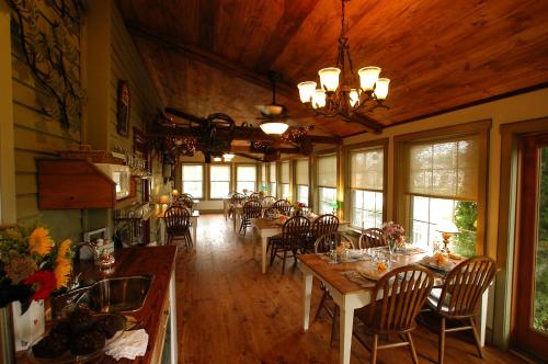 a dining room with tables and chairs and windows at 1825 Inn Bed and Breakfast in Palmyra
