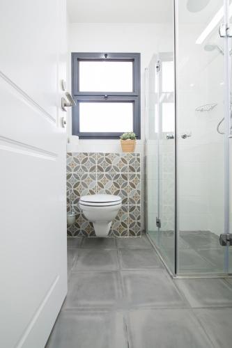 a bathroom with a toilet and a window at HaBaitBe Matityahu By Domus in Beer Sheva