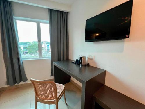 a hotel room with a desk and a television on the wall at 1 Hotel Mahkota Cheras in Kampong Perimbun