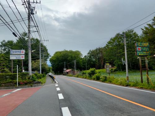 an empty road with a person riding a bike on the side at Ondolphin in Narusawa