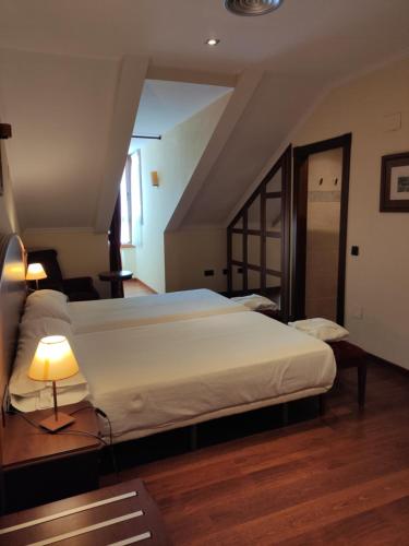a bedroom with a large white bed and a lamp at Hotel Palacio de la Magdalena in Soto del Barco