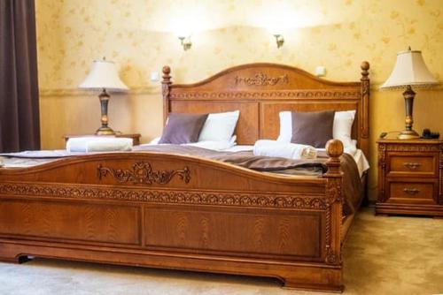 a large wooden bed in a room with two lamps at Pigy in Tatariv