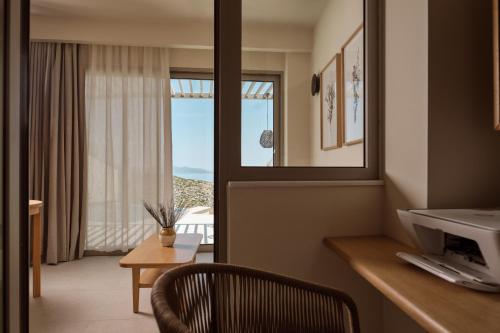 VolímaiにあるYoma Cove Suitesの窓と机と椅子のあるホテルの部屋