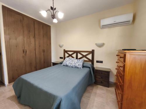 Un dormitorio con una cama y un armario de madera. en Casa Montaña, en Arriate