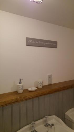 a bathroom with a sink and a sign on the wall at The Barn at Cae Bach in Gwalchmai
