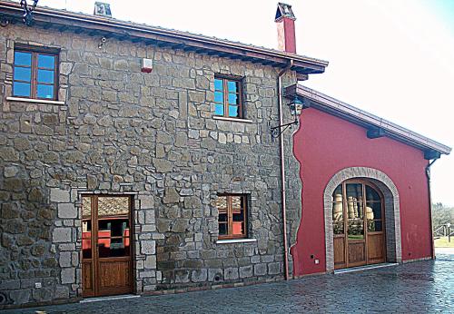 a stone building with two doors and a red at Agriturismo Podere Del Lepre in San Quirico