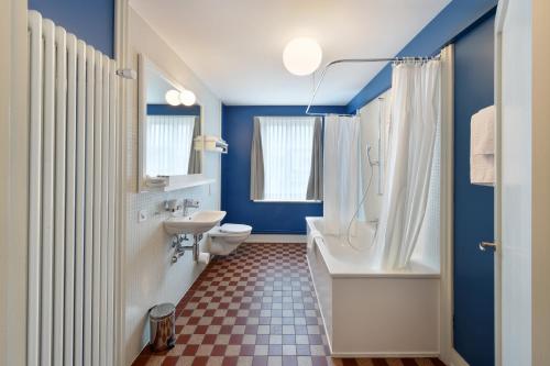 a bathroom with a white tub and a toilet and a sink at Hotel im Schlosspark in Basel