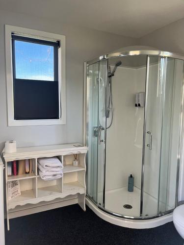 a bathroom with a glass shower with a window at Adorable studio cottage with mountain views in Staveley