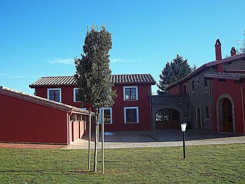 a tree in front of a red house at Agriturismo Podere Del Lepre in San Quirico