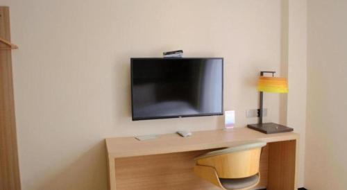 a room with a desk with a television on a wall at 7 Days Inn Zhangjiakou Chongli Yuxing Road in Zhangjiakou