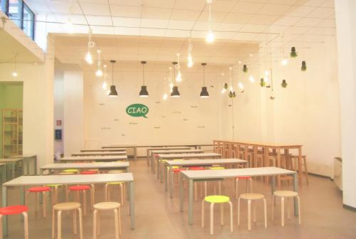 a dining room with tables and chairs and lights at Mio Hostel in Milan