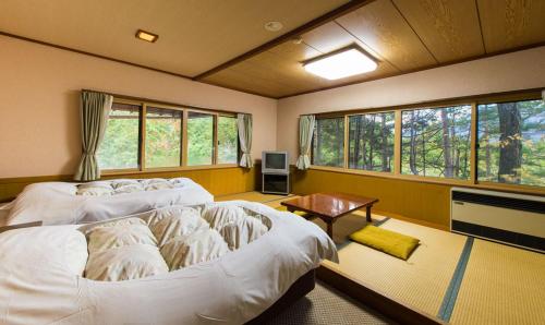 um quarto com 2 camas, uma mesa e janelas em Pension Kinoshita em Takayama