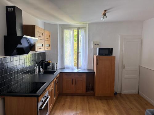 a kitchen with wooden cabinets and a black counter top at T2 dans le centre ville de Ferney in Ferney-Voltaire