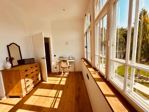 a room with large windows and a desk and a chair at luxuriöse Altbau Wohnung in Denkmal-Villa in Aidlingen