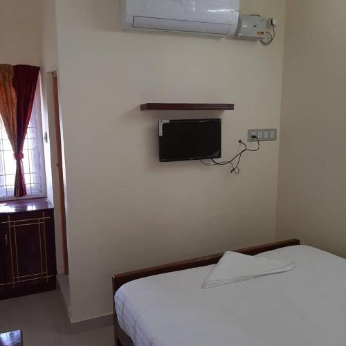 a bedroom with a bed and a tv on the wall at Thirumal residency in Tirunelveli