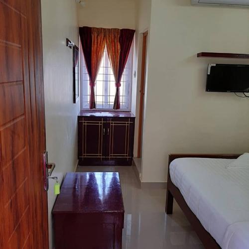 a bedroom with a bed and a window and a table at Thirumal residency in Tirunelveli
