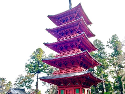 a tall red tower with trees in the background at Ondolphin in Narusawa