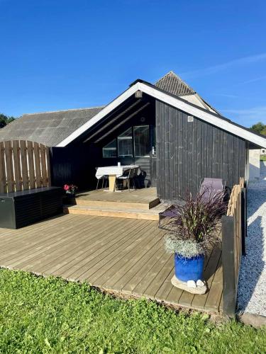 a house with a wooden deck in front of it at Feriehytte - Lille Knudsgaard in Løkken