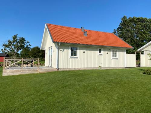 a white building with an orange roof on a yard at Hansingastugan Bed and Kitchen Guesthouse in Varberg