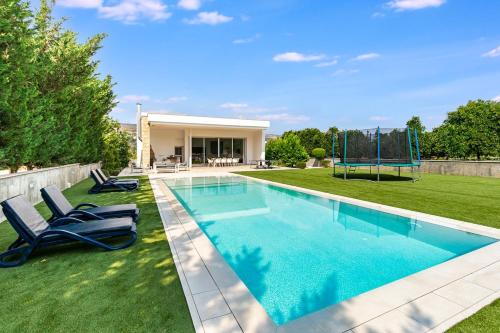 a swimming pool with two chairs and a playground at Goudi Residence in Goudhi