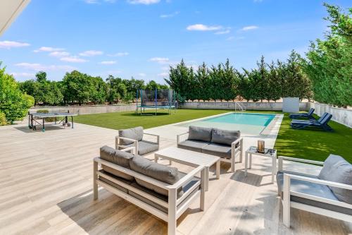 a patio with lounge chairs and a swimming pool at Goudi Residence in Goudhi