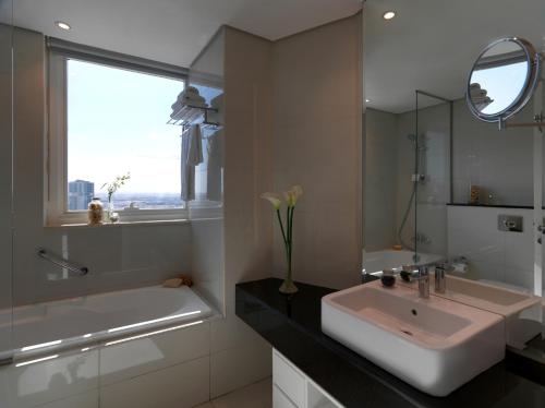 a bathroom with a sink and a tub and a mirror at DAMAC Maison Canal Views in Dubai