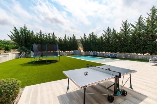 a ping pong table on a patio next to a pool at Goudi Residence in Goudhi