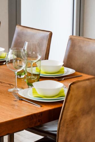a wooden table with plates and wine glasses on it at Goudi Residence in Goudhi