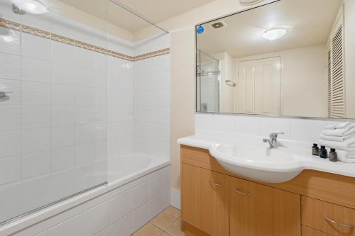 a white bathroom with a sink and a tub at Turtle Beach 250 in Gold Coast