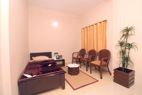 a bedroom with a bed and chairs and a table at HIGHLAND Hills in Coonoor