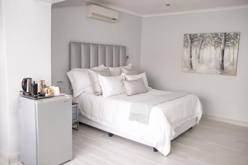 a white bedroom with a bed with white sheets and pillows at Augusta Palms in Centurion