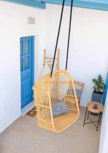 a rattan swing in a room with a blue door at YouGa Nest in Vívlos