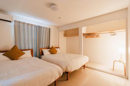 a hotel room with two beds and a window at Geisha Blue Ryusenji in Kasugai