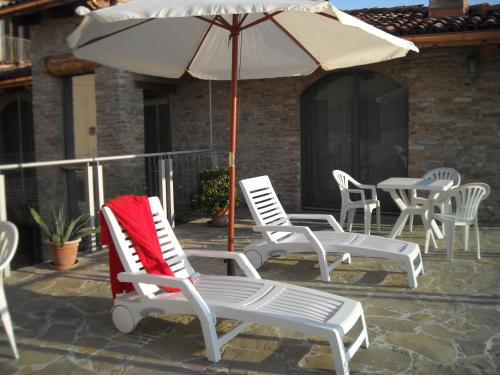 un grupo de sillas y una sombrilla en un patio en Casaforte Alba In Langa, en Mango