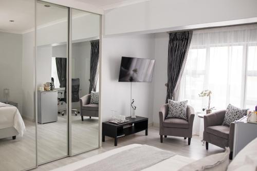 a bedroom with a bed and chairs and a mirror at Augusta Palms in Centurion