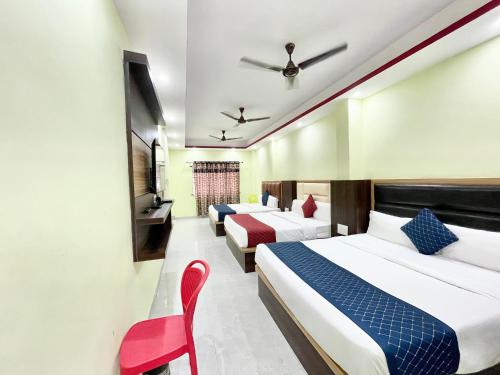a hotel room with two beds and a red chair at Hotel Premium LAXMIVILLAS ! Varanasi, Near Kashi Vishwanath Temple And Railway station, Fully Air conditioned & Spacious Room - Prime Location wifi- Lift and Room Service Facilities, BEST HOTEL IN VARANASI in Varanasi