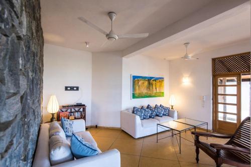 a living room with two couches and a stone wall at Jetwing Kottukal Beach House in Arugam Bay