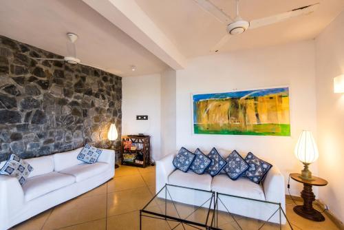 a living room with two white couches and a stone wall at Jetwing Kottukal Beach House in Arugam Bay