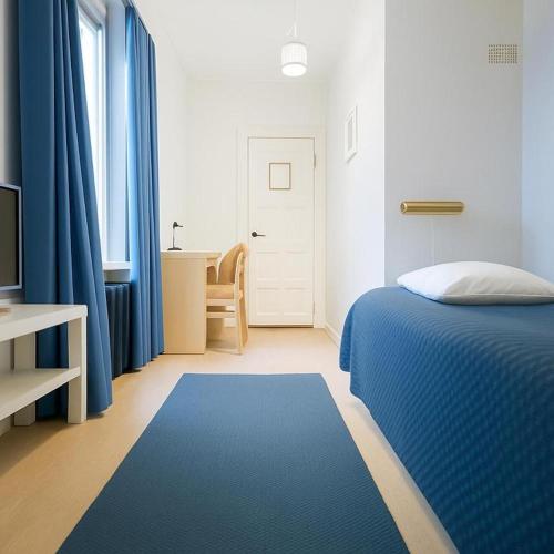 a bedroom with a blue bed with blue curtains and a desk at Senate Hotel in Helsinki