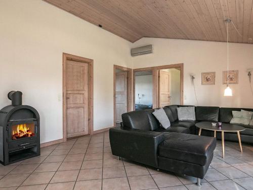 a living room with a black leather couch and a fireplace at 12 person holiday home in Hals in Hals