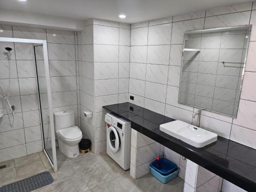 ein Badezimmer mit Toilette, Waschbecken und Waschmaschine in der Unterkunft Villa Germania in Jomtien Beach