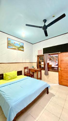 a bedroom with a bed and a ceiling fan at Sawitri Homestay in Padangbai