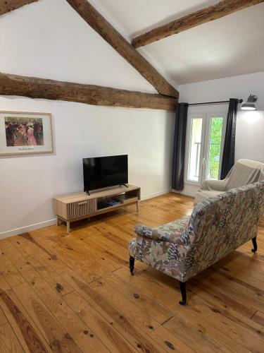 un soggiorno con un divano e una televisione di La Maison d'Alys - Le Cagnard a Cabannes