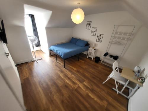 a living room with a blue bed and a wooden floor at 43 Deluxe London Ensuites in London