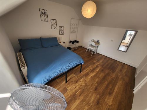 a small bedroom with a blue bed and a wooden floor at 43 Deluxe London Ensuites in London