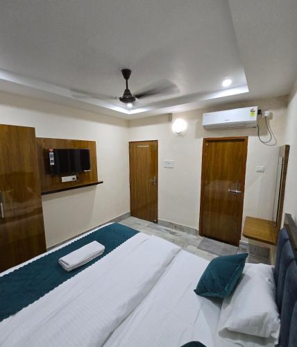a bedroom with a large white bed and a tv at Hotel Premium RUDRA GUEST HOUSE ! Varanasi, Near Kashi Vishwanath Temple And Ganga Ghat, Fully Air conditioned & Spacious Room - Prime Location BEST HOTEL IN VARANASI in Varanasi
