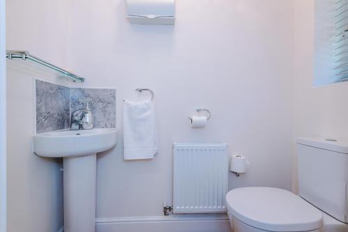 a white bathroom with a toilet and a sink at Long Term Stay 4 Bed 3 Bath & Parking Wrexham in Wrexham