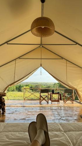 a person laying on a bed in a tent with a view at Veilscape Mara Camp in Masai Mara