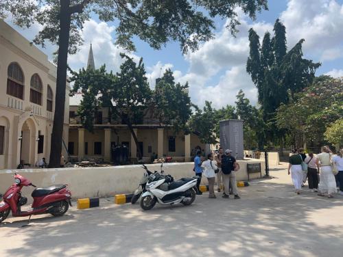 a group of people standing next to two scooters at Mango Apartment Hotel 芒果公寓酒店 in Zanzibar City