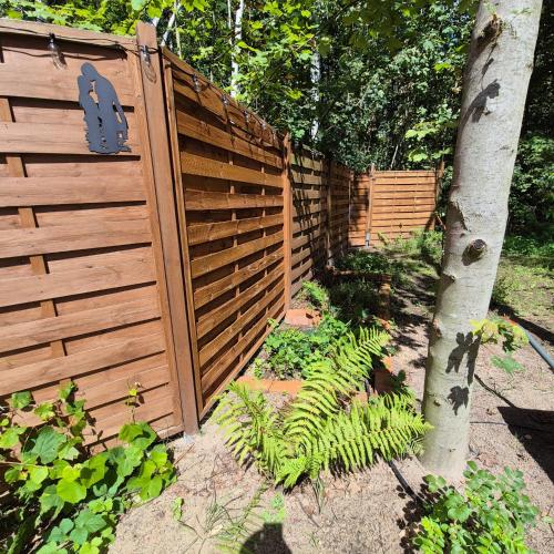 a wooden fence in a garden with a tree at Apartament nad jeziorem Strykowskim in Sapowice